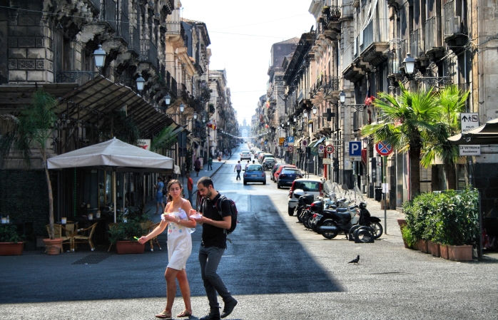 Un cuplu ce ia prânzul, traversând strada în Catania