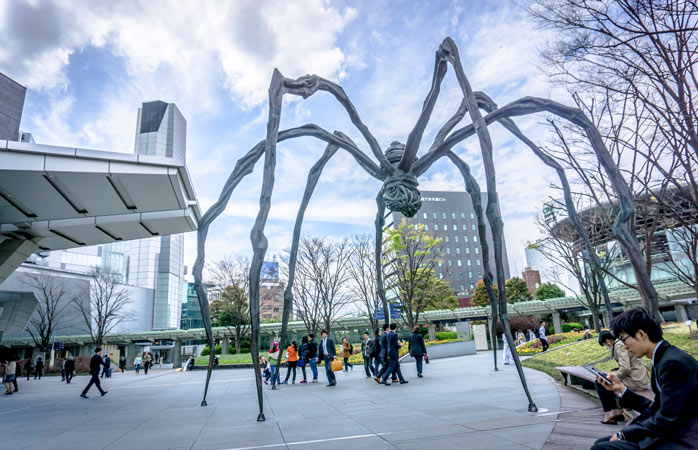 Celebra sculptură-păianjen Maman, stând sfidătoare și nemișcată în fața Turnului Mori, de pe Dealul Roppongi 