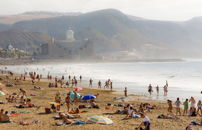 Vezi locul liber de lângă umbrela albastră? Ceva ne spune că prosopul tău s-ar potrivi acolo, pe Playa de las Canteras, precum un colier de perle pe pieptul frumos al unei doamne bine