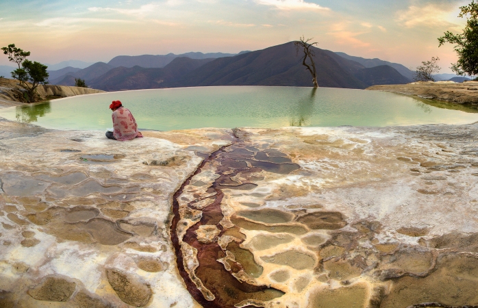 O femeie care citește o carte, la marginea unei piscine într-o formațiune calcaroasă din Oaxaca.