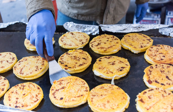 Arepas proaspete cu brânză se pregătesc de zor pe grătarele columbiene