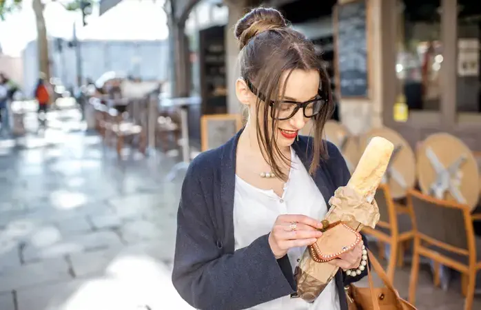 Young stylish woman buying a french baguette standing on the street in Lyon city